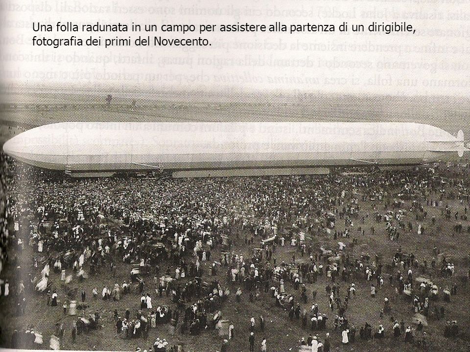 Una folla radunata in un campo per assistere alla partenza di un dirigibile, fotografia dei primi del Novecento.